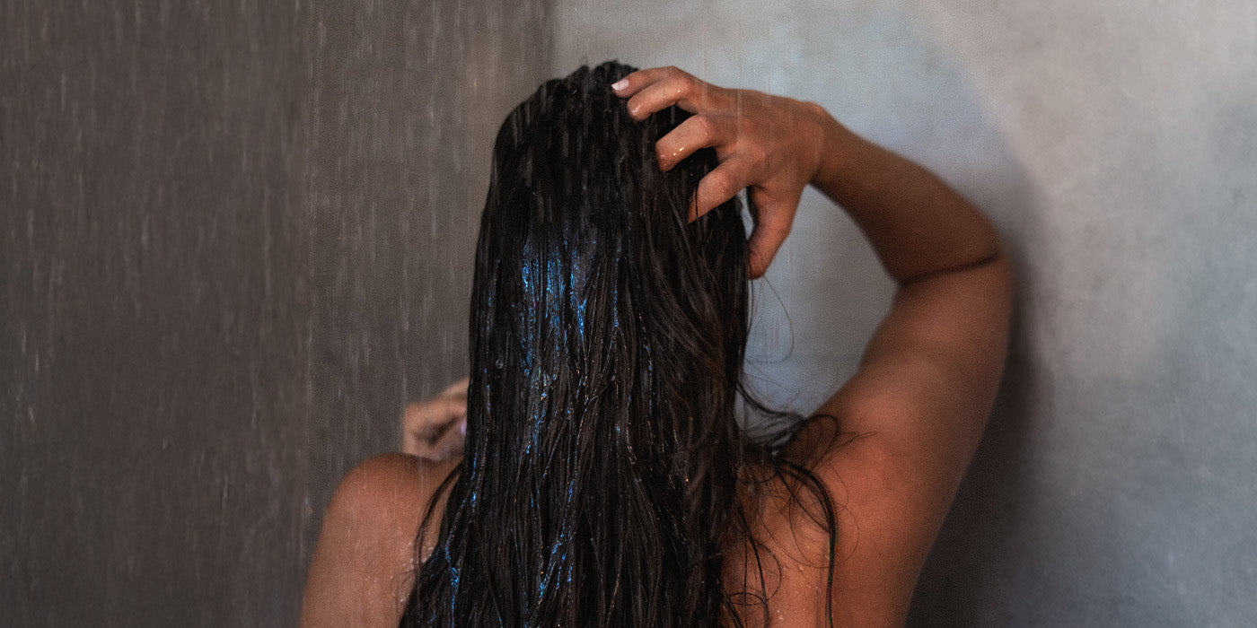 Frau wäscht sich in der Dusche die Haare