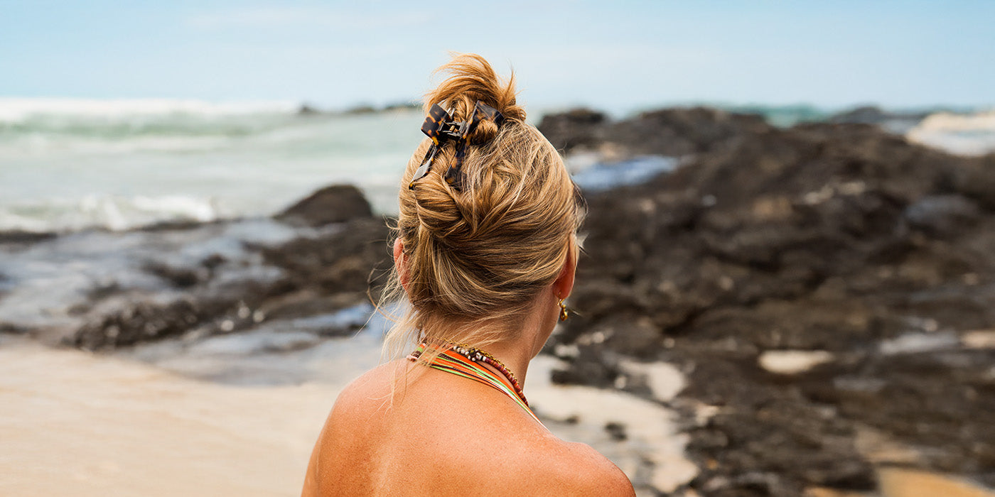 Frau ist zum Strand gekehrt und man sieht ihren Rücken, wie auch Ihre Frisur
